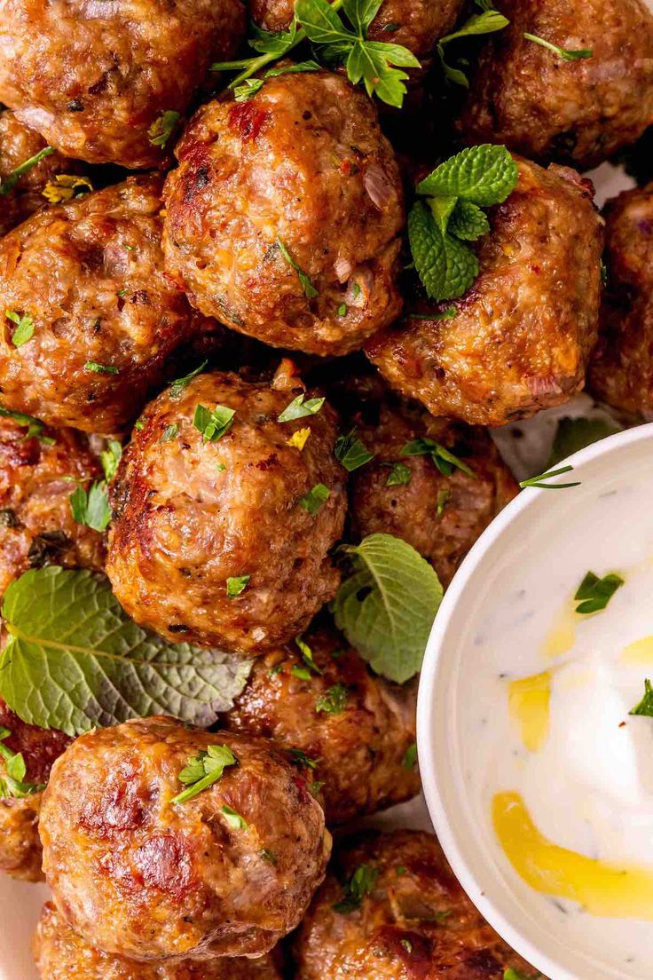 meatballs with yogurt and mint garnish on a white platter