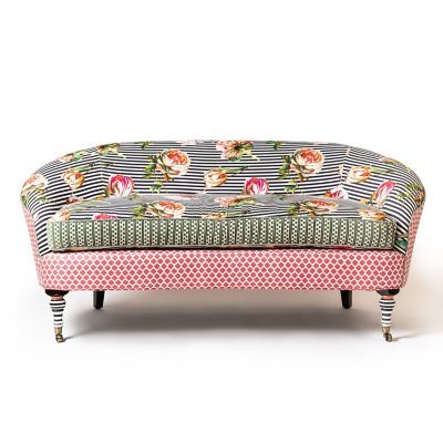 an upholstered bench with flowers and stripes on the top, in front of a white background