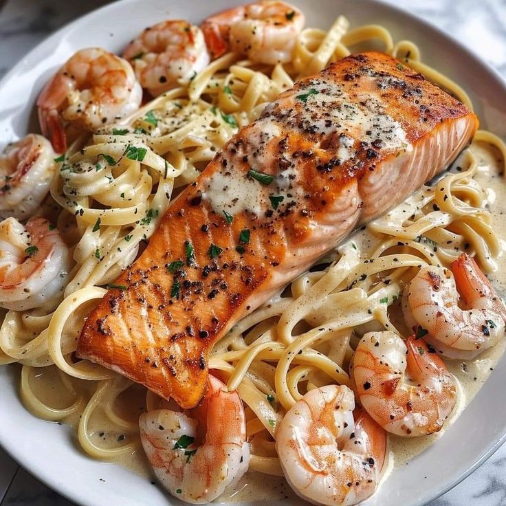 a white plate topped with pasta and salmon