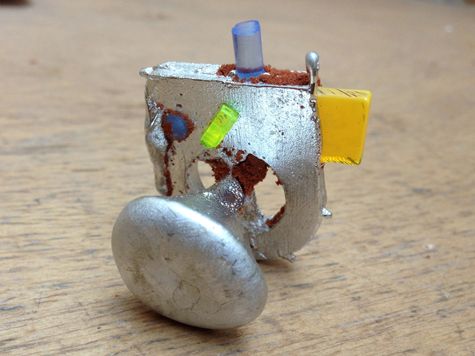 a metal object sitting on top of a wooden table next to a yellow and blue marker