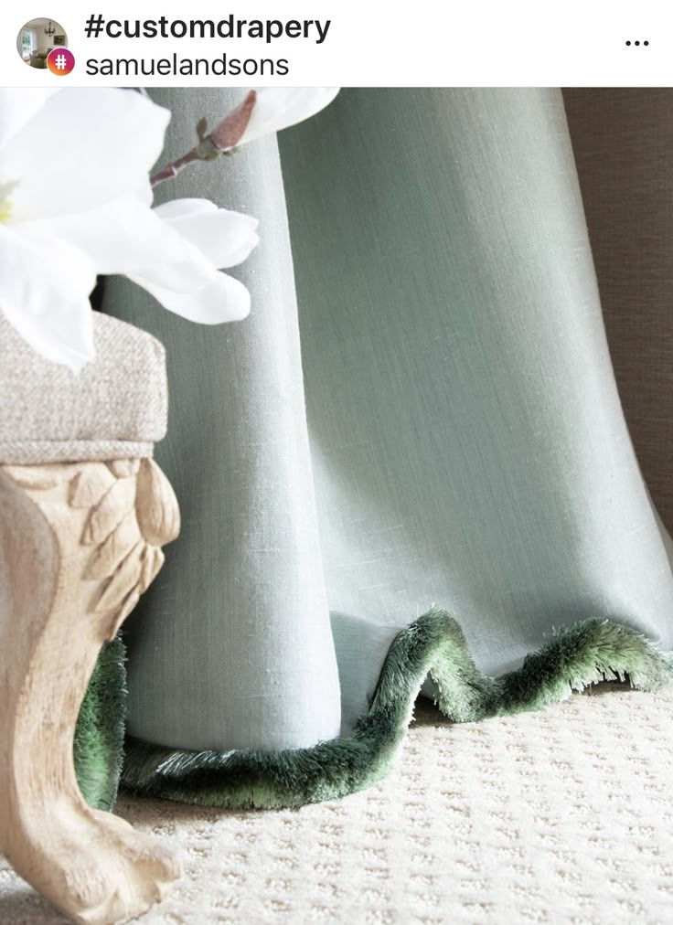 a white flower sitting on top of a table next to a curtain