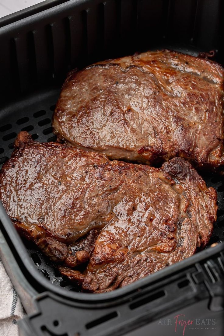 two steaks being cooked in an air fryer