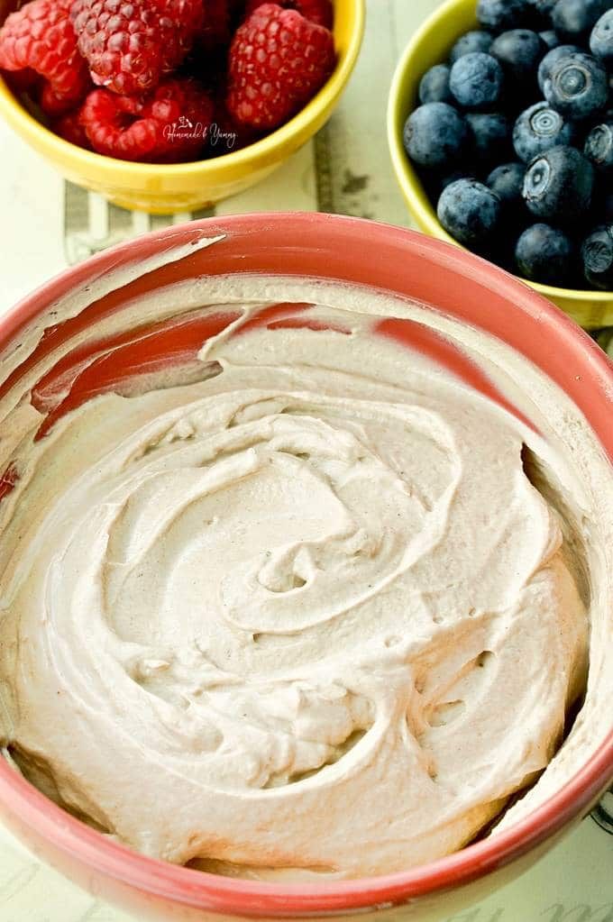 three bowls filled with different types of fruit on top of a white tablecloth next to blueberries and raspberries