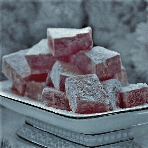 several pieces of cake sitting on top of a silver tray covered in powdered sugar