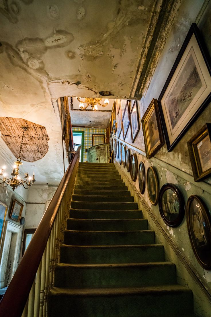 an old staircase with framed pictures on the wall