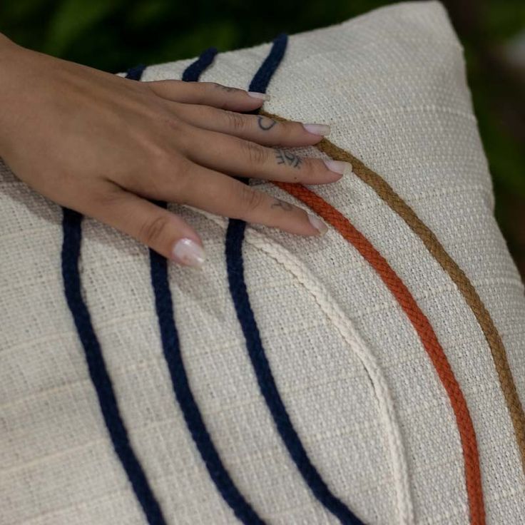 a woman's hand on the back of a pillow with stripes and rings around it