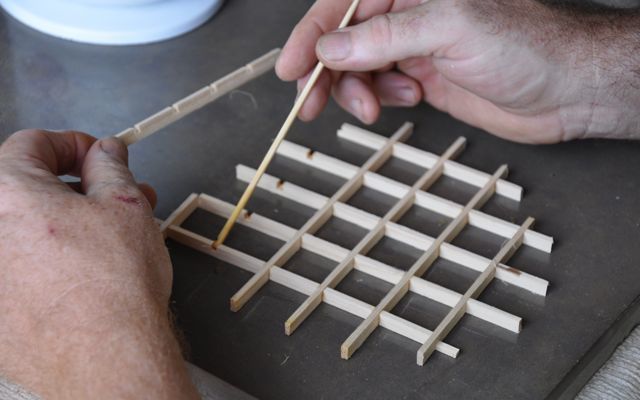 two hands are holding matches and placing them into an abacus on a tray with sticks