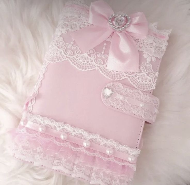 a pink book with lace and pearls on it sitting on a white furnishing