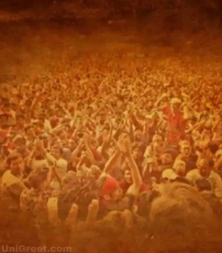 a large group of people standing in front of a crowd with their hands up to the sky