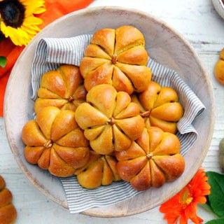 a white bowl filled with bread sitting on top of a table next to orange flowers