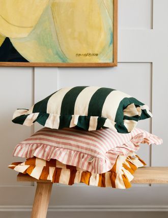 three pillows stacked on top of each other in front of a painting and wooden bench