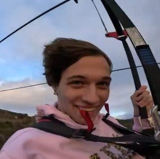 a woman is smiling while holding onto her skis with the sky in the background