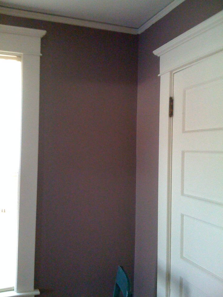 an empty room with purple walls and white trim on the door, window and chair