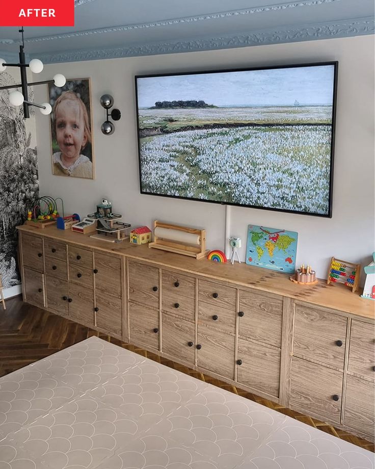 a bed room with a large flat screen tv on the wall and wooden dressers