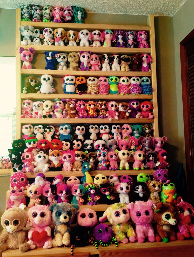 a shelf filled with lots of different kinds of stuffed animals on top of wooden shelves