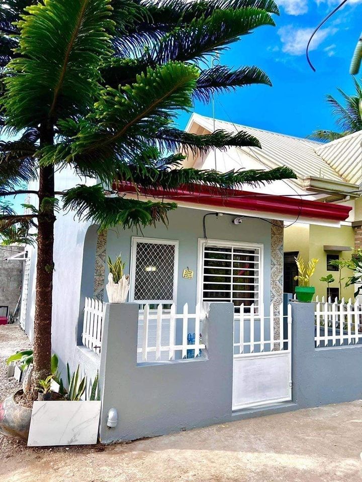 a small house with white railings and palm trees