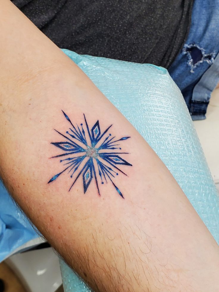 a tattoo on the arm of a person with a blue and white star in it