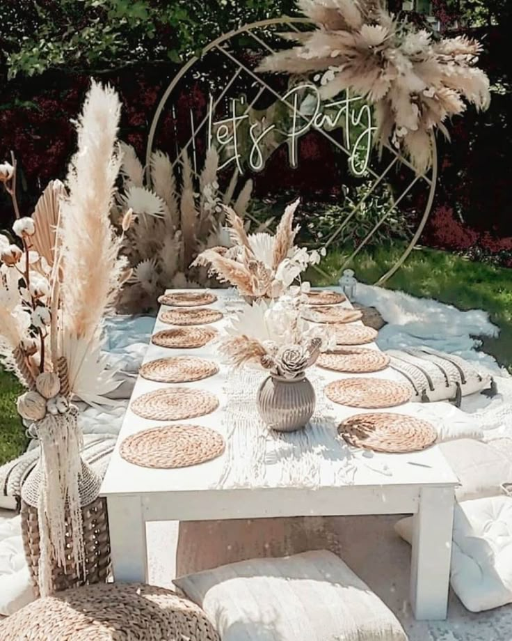 an outdoor table set up for a party with white and brown decorations on top of it