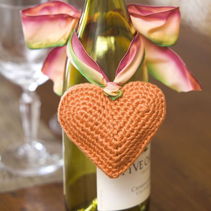 a crocheted heart sitting on top of a wine bottle