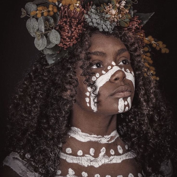 a woman with white paint on her face and flowers in her hair