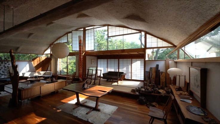 an open living room with lots of windows and wooden furniture on the floor in front of them