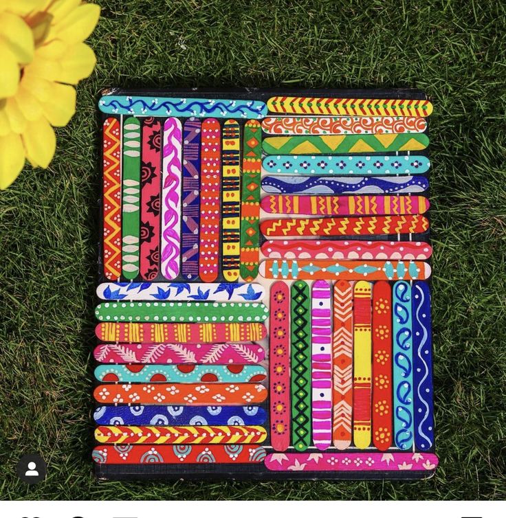 several different colored bracelets laying on top of each other in the grass next to a yellow flower