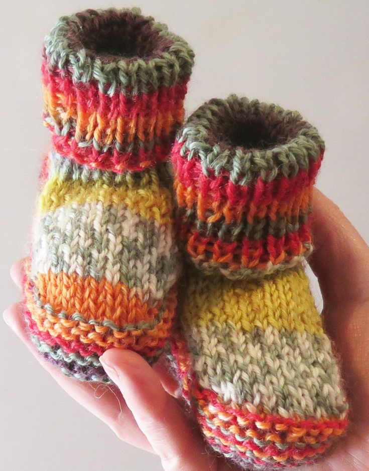 someone is holding two knitted baby booties in their hand