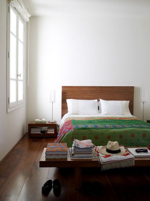 a bed sitting on top of a wooden floor next to a window