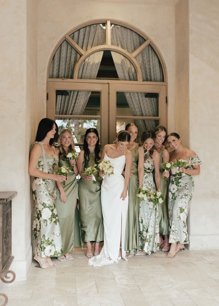 a group of women standing next to each other in front of a doorway with flowers