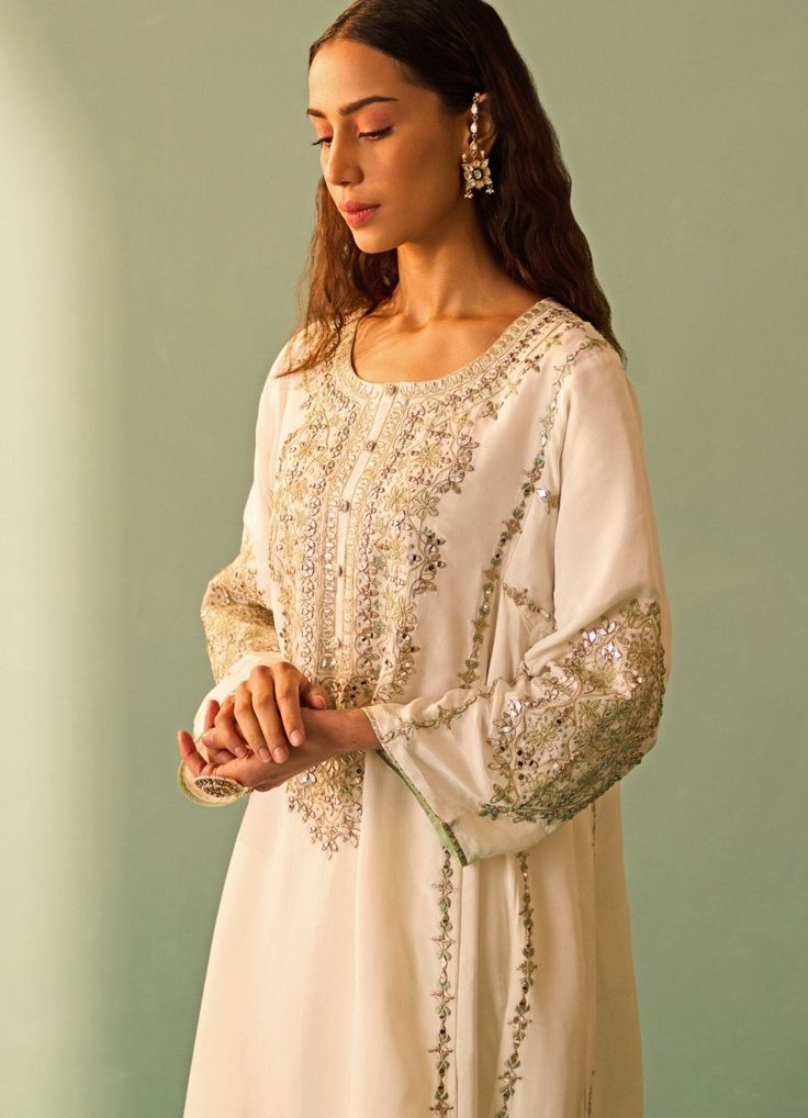 Features an ivory kurta set embroidered with sea green resham work and highlighted with mirror and gota patti.. Teamed with a sea green silk embroidered dupatta. Composition: Silk Care: Dry Clean Only and Vacuum Storage This product can be customised for sleeves, length of blouse and neckline Delivery : 4-6 weeks as the product is hand crafted. For more information and sizes please contact fabiliciousfashion@gmail.com or visit our Copenhagen studio.About the Designer : Angad Singh's journey in t White Mirror Work Kurta For Diwali, White Kurta With Mirror Work For Diwali, Festive White Kurta With Mirror Work, Diwali White Kurta With Mirror Work, Designer Cream Salwar Kameez With Gota Work, Designer Off White Kurta With Mirror Work, White Dola Silk Straight Kurta, Off White Mirror Work Kurta For Designer Wear, White Silk Anarkali Set For Eid