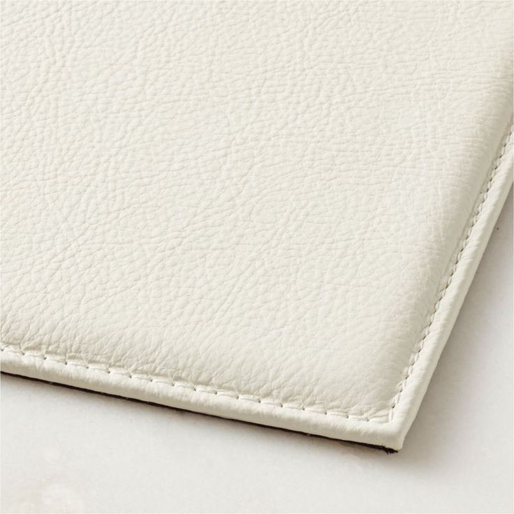 a white leather textured surface with stitching