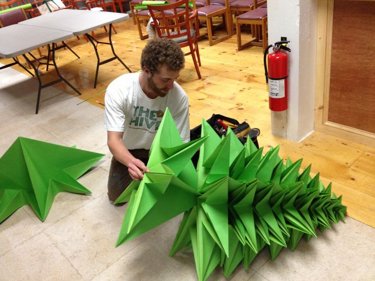 a man kneeling down next to green origami stars