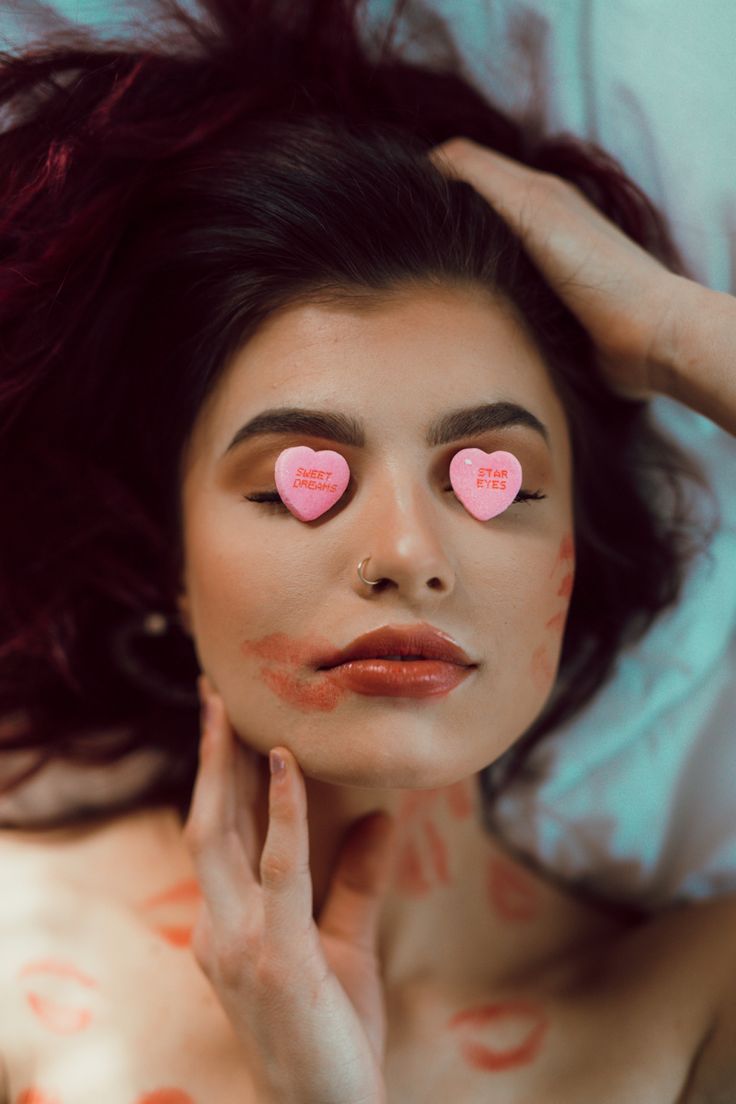 a woman with pink hearts painted on her face and hands in front of her face