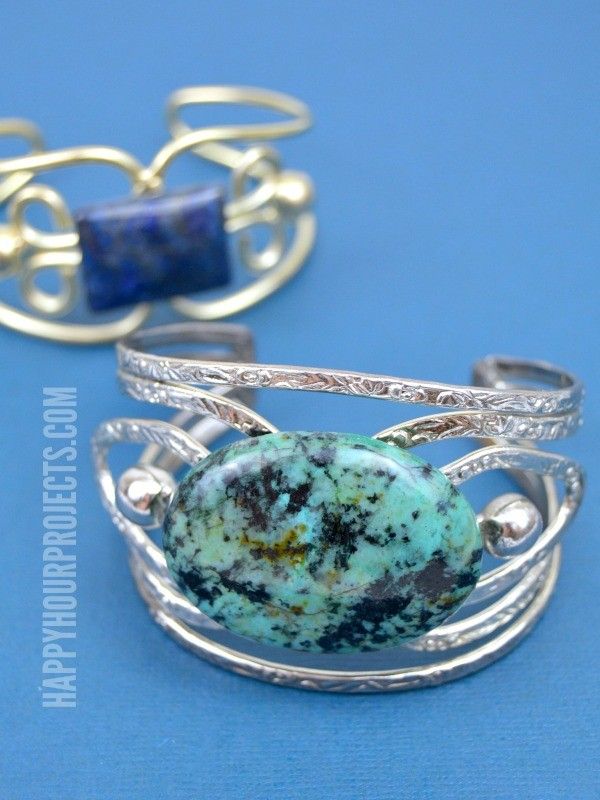 two pieces of jewelry sitting next to each other on a blue surface with silver wire