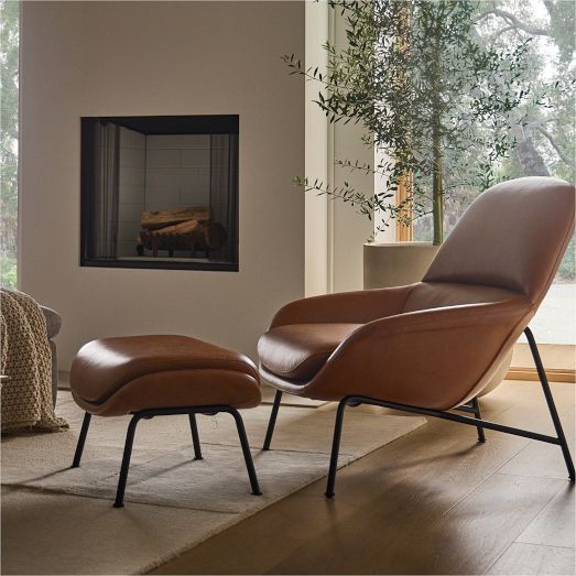 an egg chair and ottoman in front of a fireplace