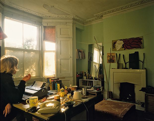 a woman sitting at a desk in front of a window with sunlight streaming through the windows