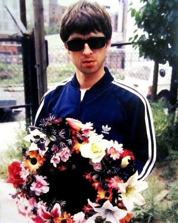 a man wearing sunglasses holding a flower wreath