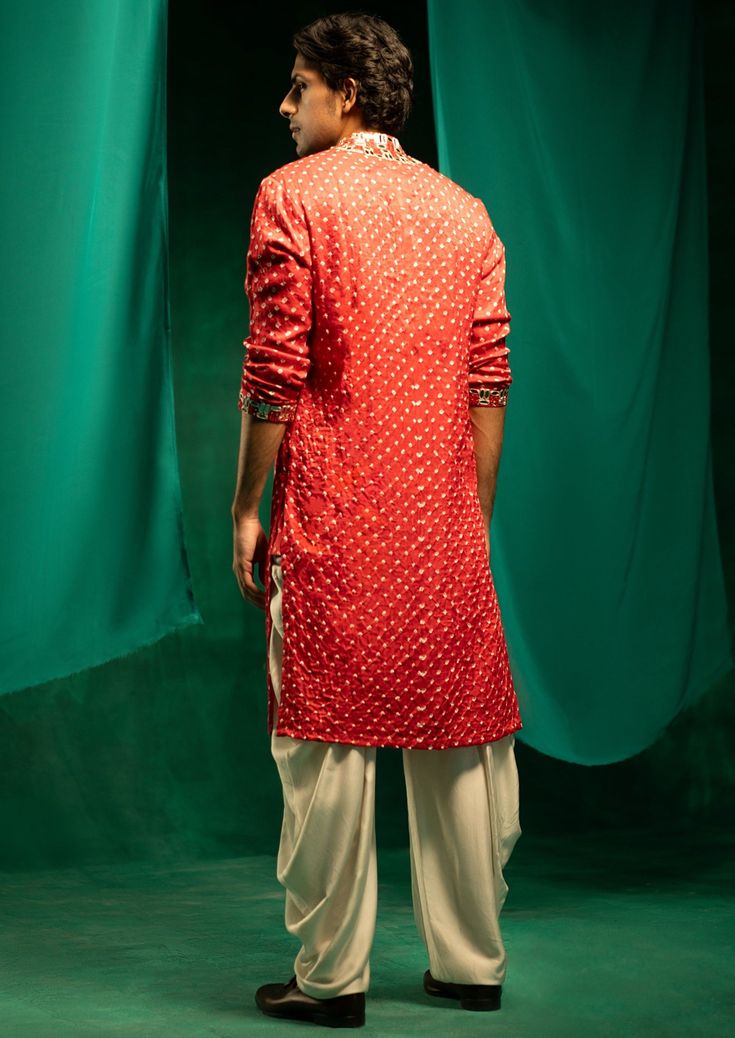 Made in gajji silk, this hand tied and dyed bandhani fabric has been designed by us & crafted by master artisans in kutch. It is styled with parsi gaara embroidery patterns designed by our team. Silk Bandhani Print Straight Kurta, Festive Transitional Bandhani Print Kurta, Festive Bandhani Print Kurta For Transitional Season, Red Cotton Silk Kurta With Chikankari Embroidery, Red Tussar Silk Kurta For Navratri, Red Silk Kurta For Puja, Red Traditional Kurta With Mirror Work, Traditional Red Kurta With Mirror Work, Silk Bandhani Print Kurta For Navratri