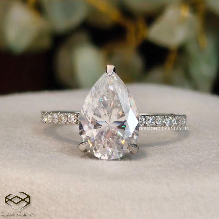 a pear shaped diamond ring sitting on top of a table