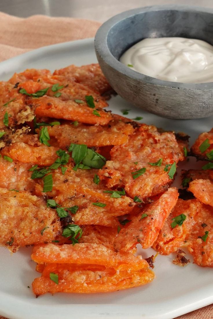 some fried food on a white plate with a bowl of ranch dressing