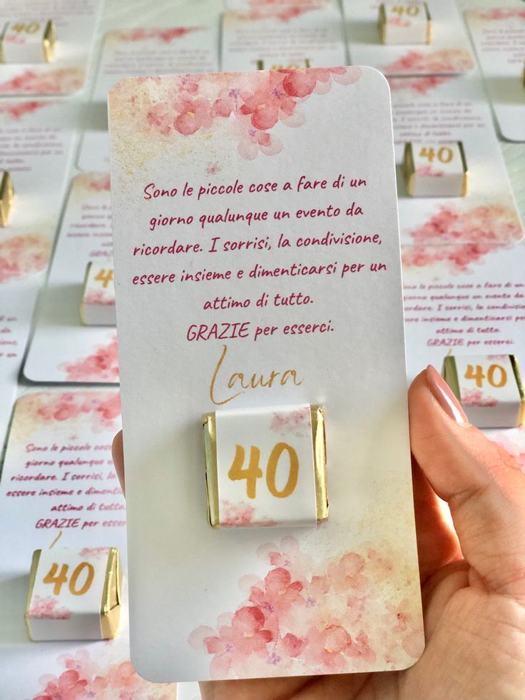 a person holding up a card with pink flowers on it and the number forty written in gold