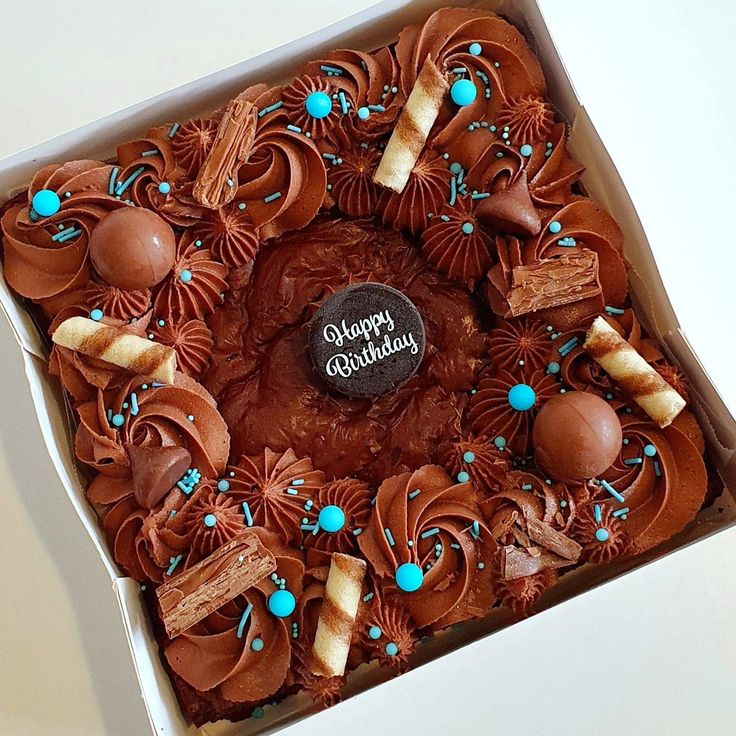 a birthday cake with chocolate frosting and blue sprinkles in a box