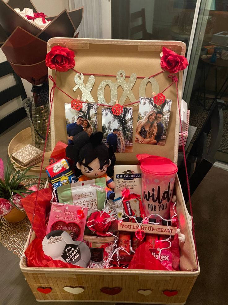 an open suitcase filled with valentine's day items and gifts on a table next to a vase