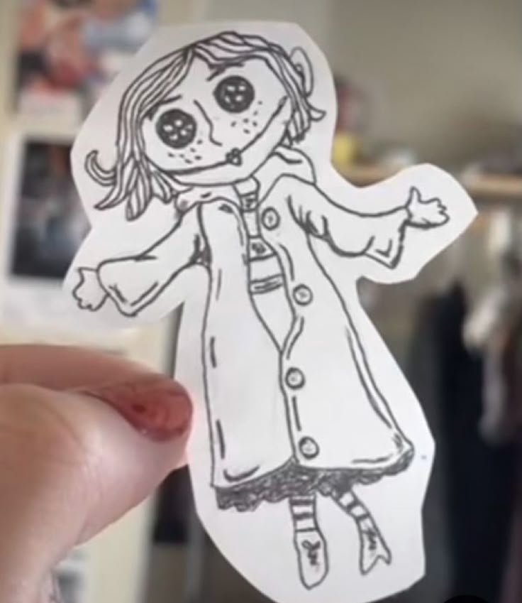 a person holding up a paper cut out of a doll