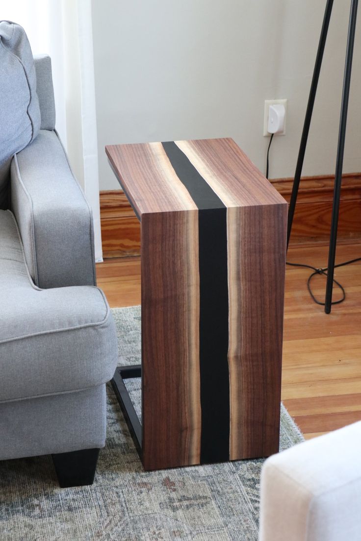 a wooden table sitting on top of a rug next to a gray couch in a living room