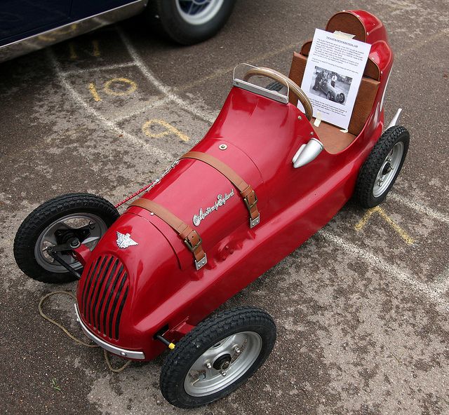 a red race car sitting on top of a parking lot