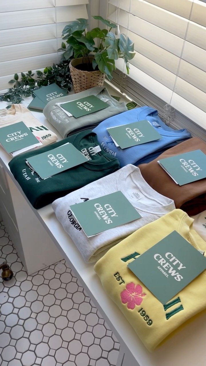 several shirts are lined up on a counter in front of a window with white shutters