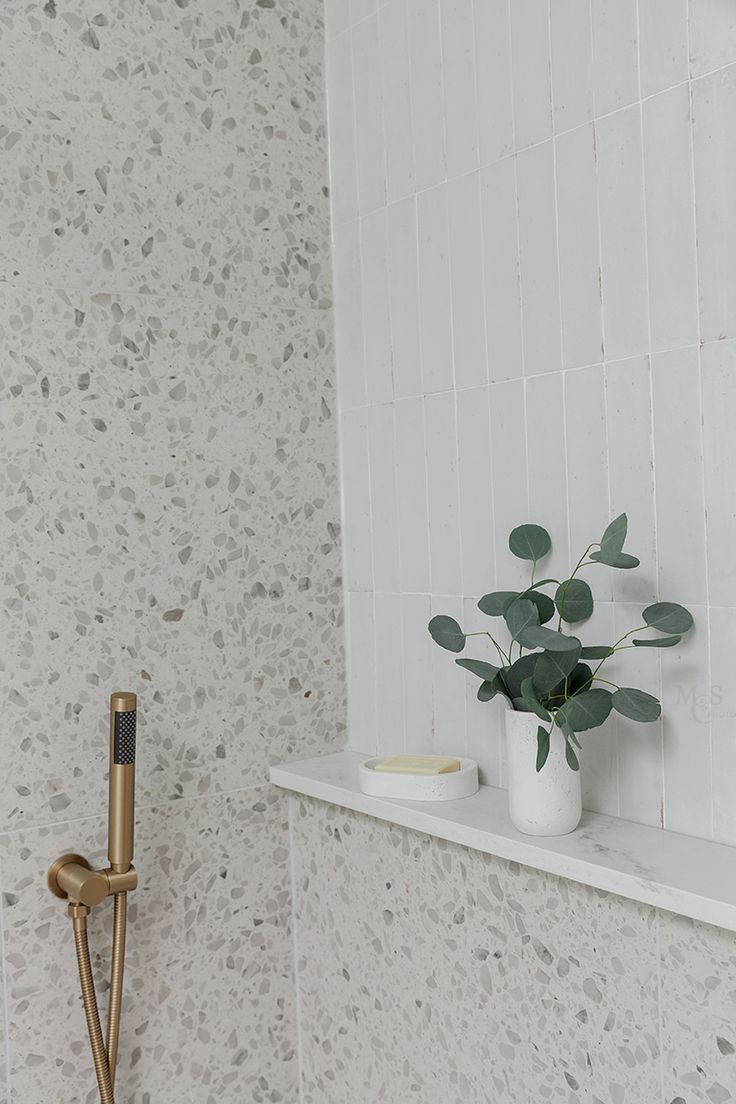 a bathroom with a white tiled wall and gold faucet