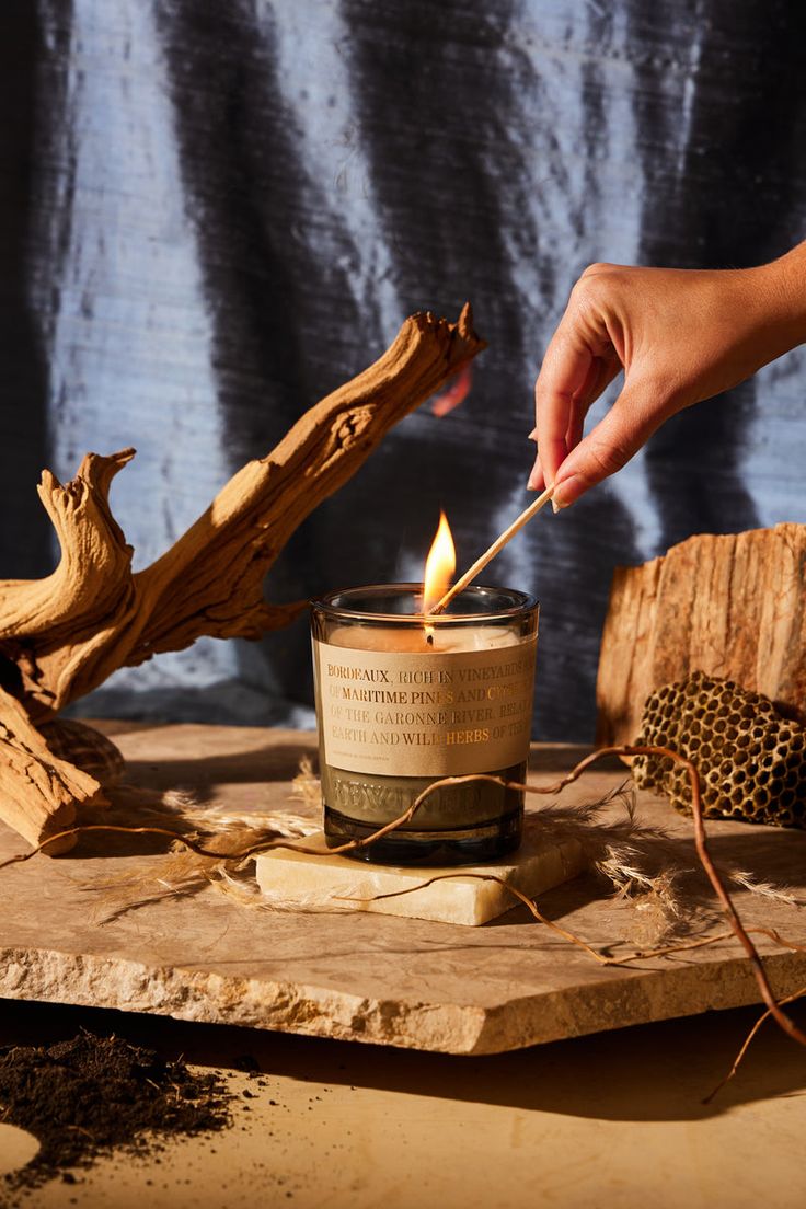 a person lighting a candle on top of a piece of wood with other items around it