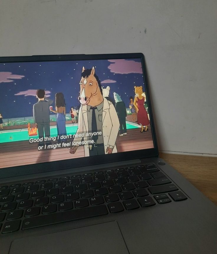 an open laptop computer sitting on top of a wooden table next to a cartoon character